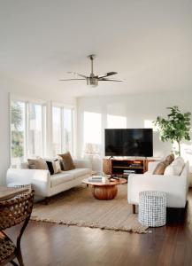 a living room with white furniture and a flat screen tv at Marshfront 5BD Oasis Pool Yard & Steps to Beach in Folly Beach