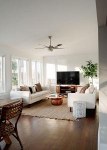 a living room with white furniture and a flat screen tv at Marshfront 5BD Oasis Pool Yard & Steps to Beach in Folly Beach