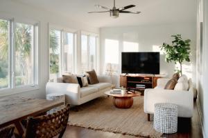 a living room with white furniture and a flat screen tv at Marshfront 5BD Oasis Pool Yard & Steps to Beach in Folly Beach +191 photos