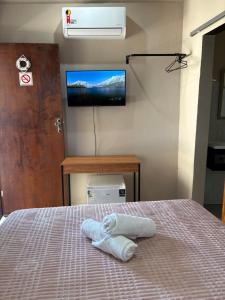 a bedroom with a bed with a tv on the wall at PouCasa Pousada in Araruama
