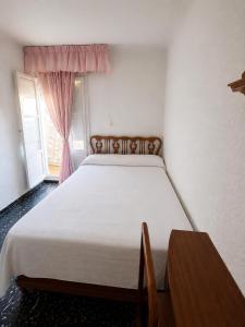 a bedroom with a white bed with a table and a window at Leidy in Alicante