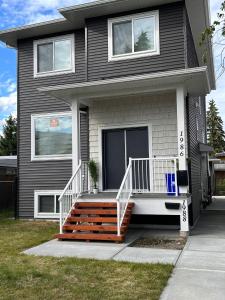 a black house with a porch with a white railing at The Ivory house in Prince George