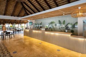 a restaurant with a bar with tables and chairs at Viva Dominicus Palace by Wyndham, A Trademark All Inclusive in Bayahibe