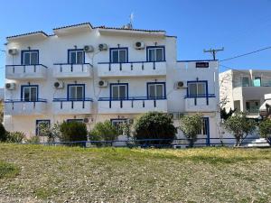 a white building with blue balconies on it at Gennadi Sun Apartments 500m from the beach in Gennadi +52 photos