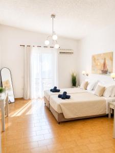 a white bedroom with a large bed and a table at Gennadi Sun Apartments 500m from the beach in Gennadi