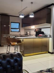a kitchen with brown cabinets and a black leather couch at 2Bedroom Luxury hotel apartment Fourways in Johannesburg