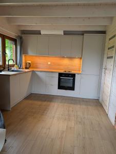 a kitchen with white cabinets and a wooden floor at Sielski Domek Na Wzgórzu in Sulęczyno