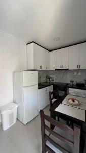 a kitchen with a table and a white refrigerator at Kloa Apartments in Orikum