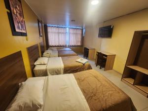 a hotel room with four beds and a television at Hotel Palace in Huancayo