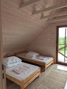 two beds in a wooden room with a window at Sielski Domek Na Wzgórzu in Sulęczyno