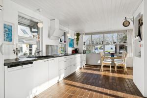 a kitchen with white cabinets and a table with chairs at Main House - Rolsø Retreat in Knebel