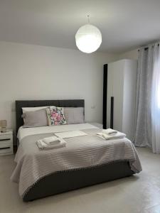 a white bedroom with a large bed with two towels on it at Kloa Apartments in Orikum