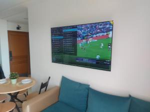 a tv hanging on a wall with a couch and a table at Cozy Studio Near Beach with Pool Access in Martil