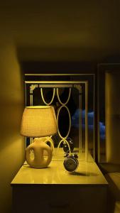 a table with a lamp and a clock on it at غرف سكون Vip للأجار اليومي والاسبوعي in Al Khawḑ