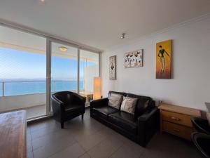a living room with a black couch and a chair at Oceana Suites Costa Montemar in Concón