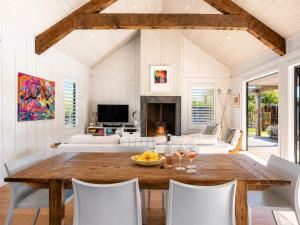 a living room with a wooden table and chairs at Blackpool Boathouse - Stay Waiheke in Oneroa