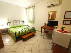 a bedroom with a bed and a desk and a television at B&B Profumo di Zagara in Taormina