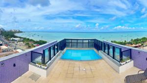 a balcony with a swimming pool and the ocean at Vacanze - Neo in Maceió