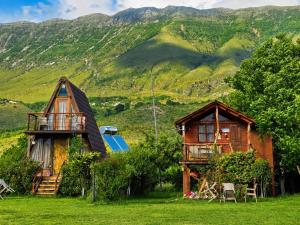 two houses in a field with mountains in the background at Life on the farm in Nepravishtë