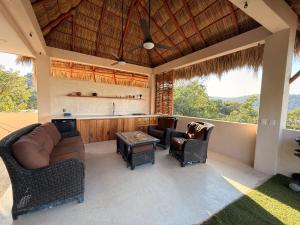 a living room with a couch and chairs and a kitchen at Casa Maracuyá Chacala in Chacala +38 photos