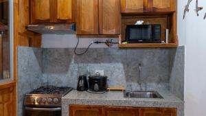 a kitchen with a stove and a sink and a microwave at Mar de Jade in Colán