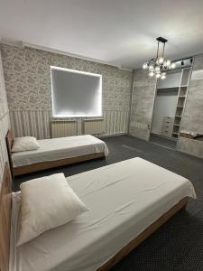 a bedroom with two beds and a large window at Aigul Hostel in Shymkent