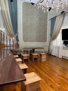 a room with tables and benches and a large screen at Aigul Hostel in Shymkent +19 photos