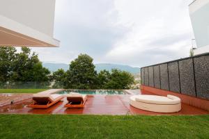 a house with two lounge chairs and a swimming pool at Hilltop Villa Tirana in Mjull-Bethore