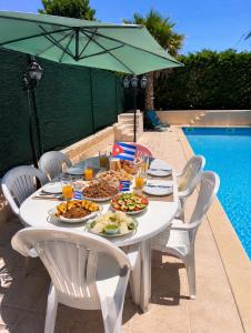 a white table with food on it next to a pool at La Escapade Cubaine in Villeneuve-sur-Lot