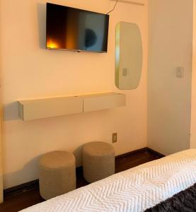 a bedroom with two stools and a tv on the wall at Hotel Montanas in Nova Friburgo