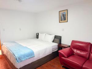 a bedroom with a bed and a red chair at Sackville Inn in Sackville