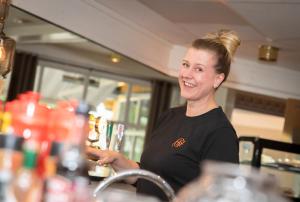 a woman standing behind a counter at a bar at Grong Hotell in Grong