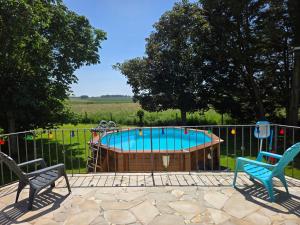 a swimming pool with two chairs next to a fence at La Parenthèse du Buisson Bailly - Jacuzzi, Détente et Bien être près de Provins in Choisy-en-Brie