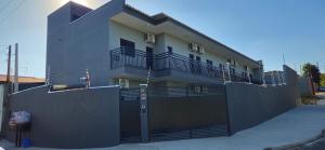 a white house with a fence and a building at Loft 3 com ar-condicionado da Rede Urbana in Indaiatuba