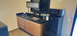 a kitchen with a counter with a refrigerator and a microwave at Loft 3 com ar-condicionado da Rede Urbana in Indaiatuba