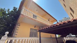 a yellow house with a balcony and a porch at Gioele apartament in Vlorë