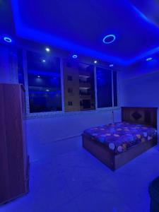 a bedroom with a bed in a room with blue lights at Abu safa home in Al Ghuşnah