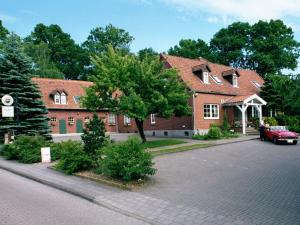 ein rotes Auto, das vor einem Backsteinhaus geparkt ist in der Unterkunft Cafe Gaubenhaus in Bad Fallingbostel