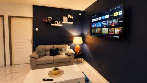a living room with a couch and a tv on a wall at Coeur A 2 in Macouria