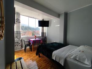 a bedroom with a bed and a table and a window at Hotel El Sol de Carhuaz in Carhuaz