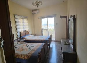 a room with two beds and a mirror and a window at Sea promenade Hostel Art Apartment in El Mîna
