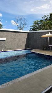 a swimming pool next to a brick wall with an umbrella at Euros Hotel in El Bordo