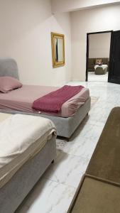 two beds sitting in a room with marble floors at Cozy rooms in Mirbāţ +7 photos
