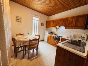 a kitchen with a table and chairs and a kitchen with wooden cabinets at Gradakia Cottages 2 in Argostoli