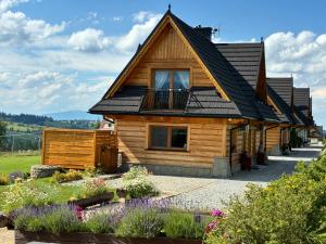 a wooden house with a balcony and flowers at Witowianskie Domki Private Jacuzzi & Mountain View near Zakopane in Dzianisz