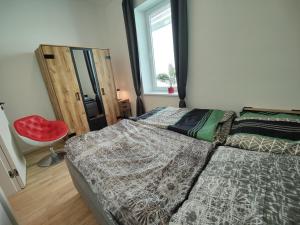 a bedroom with a bed and a red chair at Apartment Sarah LIL SIS in Tulln