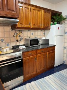 a kitchen with wooden cabinets and a microwave at Geninha Stay Aveiro in Aveiro