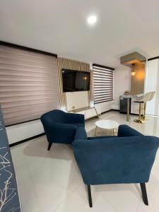 a living room with two blue chairs and a flat screen tv at Euros Hotel in El Bordo