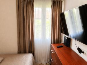 a bedroom with a dresser with a television and a window at Gunilak in Dombóvár