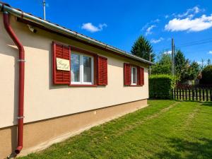 a house with red shuttered windows and a yard at Gunilak in Dombóvár